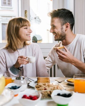 A man and woman are eating breakfast at a table.