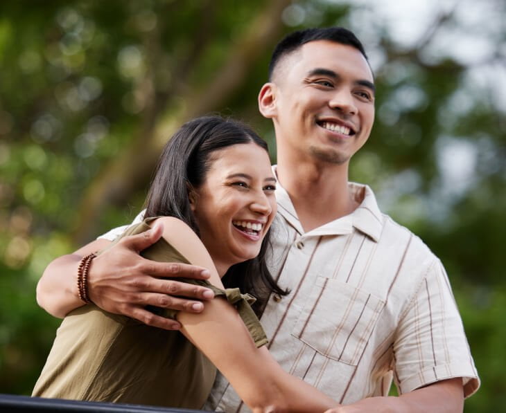 A young asian couple hugging in a park.