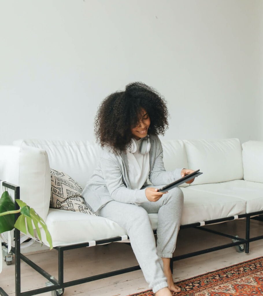A young woman sitting on a white couch with a tablet for TheraLeaf online quiz