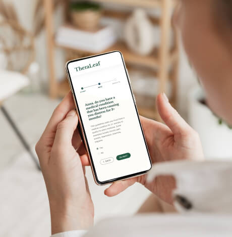 A woman holding a smartphone with TheraLeaf online quiz displaying on it.