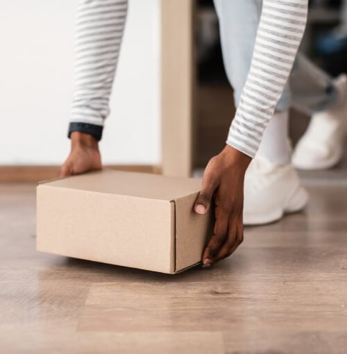 A person holding a Theraleaf delivery box on a wooden floor.
